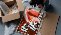 Sneakers Hanging from a Car Mirror framed print being unpacked from protective bubble wrap and a box