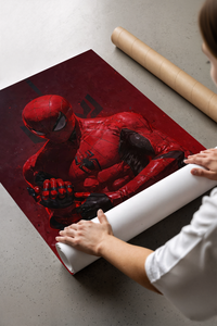 Woman unrolling the red suited Spider-Man poster on a concrete floor next to cardboard shipping tubes