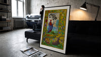 Alchemist holding a flask print in a slim black frame leaning on a dark sofa in a concrete print studio