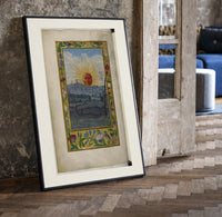 Sun with human face over town print in a black frame leaning beside a vintage door on parquet