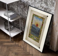 Sun with human face over town poster in a black frame leaning beside a shelf in a raw-plaster loft