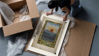 Sun with human face over town framed print being unpacked from protective bubble wrap and a box