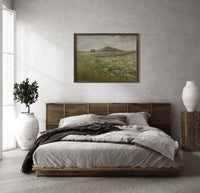 Poppy wildflower meadow landscape print in a dark wood frame above a rattan bed on a plaster wall