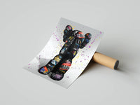 KAWS graffiti street edition standing figure with bright tags, partially unrolled matte print resting on a gray surface