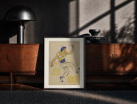 Black-framed Dancer in blue cap leaping print on a moody console with designer coffee-table books