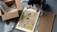 Dancer in blue cap leaping framed print being unpacked from protective bubble wrap and a box
