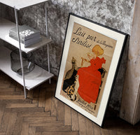 Girl in red dress drinking from bowl poster in a black frame leaning beside a shelf in a raw-plaster loft
