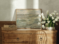 Rough seascape with breaking waves print in an oak frame on a farmhouse dresser beside white tulips