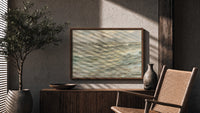 Rough seascape with breaking waves print in a wood frame above a fluted sideboard beside an olive tree