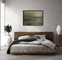 Stormy seascape with breaking waves print in a dark wood frame above a rattan bed on a plaster wall