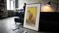 Woman taming a lion print in a slim black frame leaning on a dark sofa in a concrete print studio