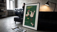 Boy playing with laundry, woman washing print in a slim black frame leaning on a dark sofa in a concrete print studio