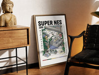 Brass-framed Super Nintendo game console with controller print leaning in a warm styled corner by a sculpture