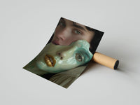 Surreal ceramic face art print shown as rolled poster draped over a brown shipping tube