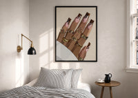 Swirl Manicure with a Heart Ring print in a black frame above a bed with striped linens