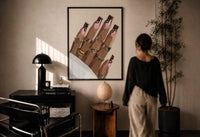 Swirl Manicure with a Heart Ring print in a black frame on a sunlit plaster wall, a woman looking on beside a mushroom lamp