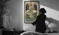 Temperance print in a slim black frame being hung on a sunlit wall in a monochrome room