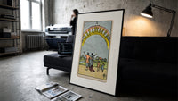 Ten of Cups tarot family print in a slim black frame leaning on a dark sofa in a concrete print studio