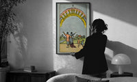 Ten of Cups print in a slim black frame being hung on a sunlit wall in a monochrome room