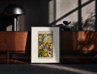 Black-framed Ten of Pentacles tarot card print on a moody console with designer coffee-table books