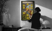 Ten of Pentacles print in a slim black frame being hung on a sunlit wall in a monochrome room