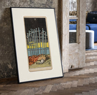 Ten Swords Tarot card print in a black frame leaning beside a vintage door on parquet
