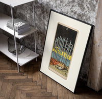 Ten Swords Tarot card poster in a black frame leaning beside a shelf in a raw-plaster loft