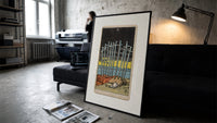 Ten Swords Tarot card print in a slim black frame leaning on a dark sofa in a concrete print studio