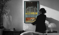 Ten of Swords print in a slim black frame being hung on a sunlit wall in a monochrome room