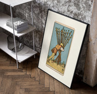 Man carrying ten wooden staves poster in a black frame leaning beside a shelf in a raw-plaster loft