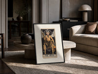 The Devil tarot card figure print in a black frame leaning on a travertine table in a sunlit lounge