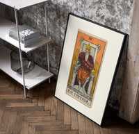 Bearded emperor on stone throne poster in a black frame leaning beside a shelf in a raw-plaster loft