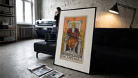 Bearded emperor on stone throne print in a slim black frame leaning on a dark sofa in a concrete print studio