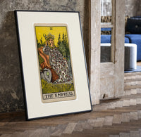 Empress on throne with crown print in a black frame leaning beside a vintage door on parquet