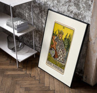 Empress on throne with crown poster in a black frame leaning beside a shelf in a raw-plaster loft