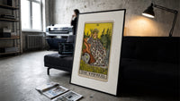 Empress on throne with crown print in a slim black frame leaning on a dark sofa in a concrete print studio