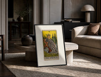 Empress on throne with crown print in a black frame leaning on a travertine table in a sunlit lounge
