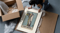Cloaked hermit holding lantern and staff framed print being unpacked from protective bubble wrap and a box