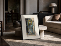 The High Priestess tarot figure print in a black frame leaning on a travertine table in a sunlit lounge