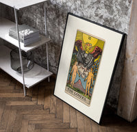 The Lovers tarot card poster in a black frame leaning beside a shelf in a raw-plaster loft