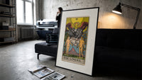 The Lovers tarot card print in a slim black frame leaning on a dark sofa in a concrete print studio