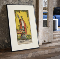 Robed magician raising a wand print in a black frame leaning beside a vintage door on parquet