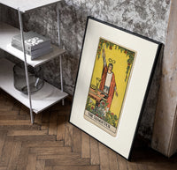 Robed magician raising a wand poster in a black frame leaning beside a shelf in a raw-plaster loft