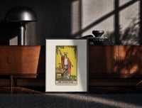 Black-framed Robed magician raising a wand print on a moody console with designer coffee-table books