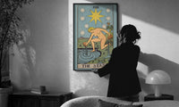 The Star print in a slim black frame being hung on a sunlit wall in a monochrome room