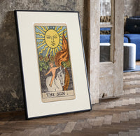 Child on white horse tarot print in a black frame leaning beside a vintage door on parquet