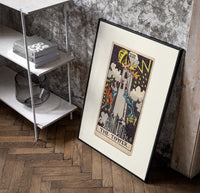 The Tower tarot card poster in a black frame leaning beside a shelf in a raw-plaster loft