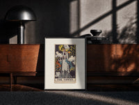 Black-framed The Tower tarot card print on a moody console with designer coffee-table books
