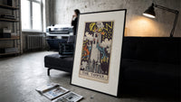 The Tower tarot card print in a slim black frame leaning on a dark sofa in a concrete print studio