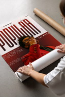Woman unrolling a The Weeknd Popular Idol Magazine Cover poster print on a concrete floor